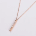 Macro view of rose gold bar pendant necklace with seven inlaid white crystals on fine chain - Rose Gold