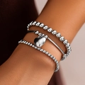 Detail of layered silver beaded bracelets with a 3D heart pendant worn on a wrist - Silver Heart Charm Triple Set Style (4559) / Silver