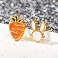 Gros plan sur les boucles d'oreilles carotte et lapin en acier inoxydable doré et émail - Lapin Carotte