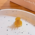 Mini yellow plastic hair claw clip with smooth finish on decorative white ceramic dish - Orange