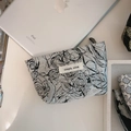Macro shot of black jacquard mini zipper pouch with simple wish label and floral texture - Grey Base Rose Pattern