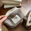 Detail view of plaid tweed makeup bags with thick white zippers and fabric labels - Beige Coffee Plaid