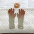 Detail of gradient knit gloves showing rib cuffs and a small compass logo patch - Dark Khaki