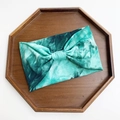 Elastic cotton tie-dye yoga headband in green with a central knot design on wood - Green Tie Dye