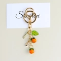 Close-up of cute persimmon keychain with orange fruit charms and a green leaf charm - Orange Pendant