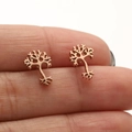 Elegant Tree of Life stud earrings in rose gold finish held against white background - Rose Gold