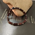 Detail of beaded bracelet with reddish-brown stones and silver spacer beads on rock - Red Jasper