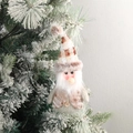 Plush Christmas gnome ornament with knitted hat and faux fur on a snowy tree branch - Santa Claus