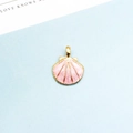 Detailaufnahme eines rosa Emaille-Muschel-Anhängers mit goldener Metallkante - Rosa