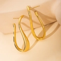 Macro view of gold irregular curved earrings with polished metallic fluid texture - U-Shape Hoop Earrings