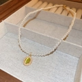 Detalle de collar de perlas bañado en oro con colgante de ojo de gato verde en estuche - Gota de Agua Verde