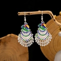 Close-up of Cloisonne peacock earrings with blue enamel details hanging on a branch - Colorful Phoenix