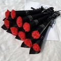 Close-up of red soap carnations in black paper cones with decorative ribbons - Carnation / Red