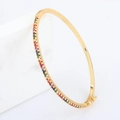 Brazalete bañado en oro de 18k con circonitas arcoíris sobre fondo de mármol - Dorado