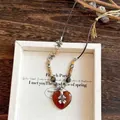 Detalle de un collar vintage con colgante de corazón de resina y cuentas de madera y metal - Estilo Colgante De Flor De Corazón / Marrón