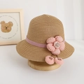 Dettaglio di un cappello di paglia per bambini con nastro a fiori rosa e piccoli ciliegi - Cappello / Marrone