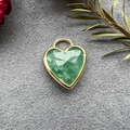 Detail of a heart-shaped green crystal pendant with gold-plated edges on suede - Green