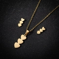 Golden heart necklace and earrings set with triple heart pendants on black background - Three Hearts / Gold