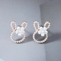 Dettaglio ravvicinato di orecchini a forma di coniglio dorato con perle bianche e fiorellini - Bianco con perla bianca