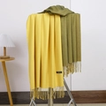 Close-up of yellow and olive green cashmere scarves with fringes on a display rack - No.11 Ginger Yellow