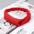 Detail of red ribbed knit headband with cross twist design on minimalist background - Knitted Bright Red