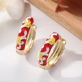 Macro shot of red enamel hoop earrings featuring white scrolls and yellow floral details - Red Base Yellow Flower