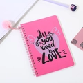 Detalle de cuaderno de espiral rosa con pompón de peluche y diseño All You Need Is Love - Corazón Escrito a Mano Rosa