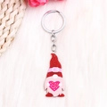Détail d'un porte-clés nain rouge à paillettes tenant un cœur rose sur un tissu doux - Gnome au Chapeau Rouge