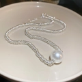Close-up of silver irregular textured chain with white pearl pendant on ceramic tray - Circle Crushed Silver Pearl Pendant Necklace