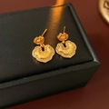 Dettaglio ravvicinato di orecchini vintage dorati con zirconi in una scatola per gioielli - Perno in Argento 925 / Placcato Oro / Serratura della Pace Dorata