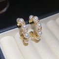 Close-up of gold-plated hoop earrings with pearls and zircon in a jewelry box - Gold