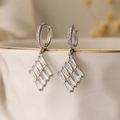 Silver geometric earrings with emerald-cut zircon hanging on a white porcelain bowl - Geometric Dangle / Silver