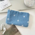 Flat lay of star print denim pouch with accessories on white desk showing its daily use - Dark Blue