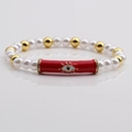 Multicolor evil eye beaded bracelet with white pearls and gold accents on grey mirror - Red