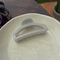 Detailed view of large 10cm marble textured claw clip in elegant cream ceramic plate - Grey/White