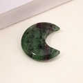 Polished anyolite crystal crescent moon pendant with ruby spots on a beige surface - Ruby Zoisite