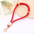 Close-up of red PU leather keychain with gold lobster clasp on artistic background - Red