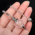 Rose quartz gemstone pendulum pendant with silver chain held against a black background - Rose Quartz