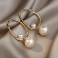 Detail of gold-plated geometric butterfly pearl hoop earrings on champagne silk background - Light Coffee Geometric