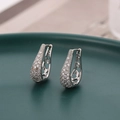 Elegant silver micro-pave teardrop earrings with hollow pattern on green ceramic tray - Silver