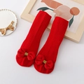 Details von roten Baby-Stricksocken mit Schleifen und Anti-Rutsch-Sohle auf Holzuntergrund - S (0-1 Jahr) / Rote Socken (Ball Rote Schleife)