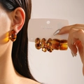 Detailed macro view of 5-piece amber resin leopard print hoop and geometric earrings - Twisted Style / Amber