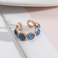 Detail of vintage gold open ring with six round deep blue gemstones and cat-eye texture - Blue Resin
