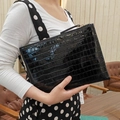 Close-up of black crocodile pattern patent leather envelope clutch with metallic zipper - Black