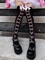 Detail of black thigh-high stockings with pink bows and crossbone prints on stone steps - Black Pink Bow