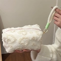 White plush cosmetic bag with floral texture and green woven handle in handheld view - Handheld Plush Beige Heart
