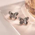 Macro detail of silver butterfly earrings with fine texture on soft silk background - Butterfly