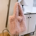 Pink plush faux fur tote bag with stylish tassels hanging in a minimalist room - Pink