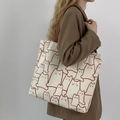 Minimalist canvas tote bag with cat print and brown handles shown on female shoulder - Beige