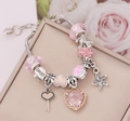 Detailed macro of pink crystal charms and love heart pendants on silver snake chain - Pink
